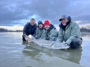 Group of fishermen showcasing their successful catch while sturgeon fishing on the Fraser River adventure