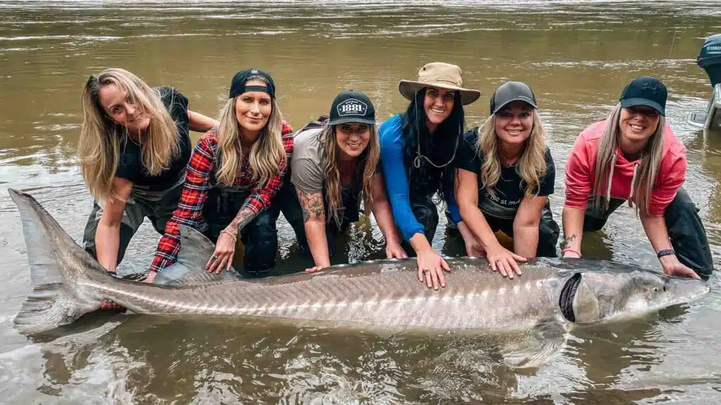 Ladies holding a massive sturgeon